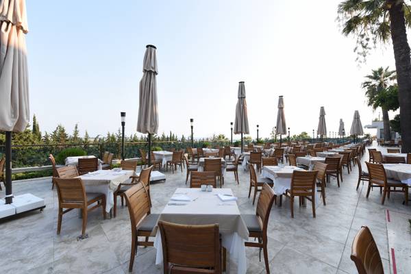 Außenterrasse des Side Star Elegance Hotels mit vielen Tischen und Stühlen, überdacht von Sonnenschirmen.