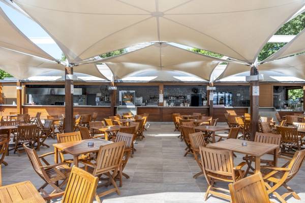 Terrasse des Side Star Elegance Hotels mit vielen Holztischen und Stühlen unter großen Sonnensegeln.