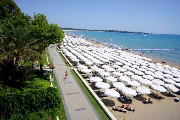 Strandansicht mit vielen weißen Sonnenschirmen und Menschen, die sich entspannen.
