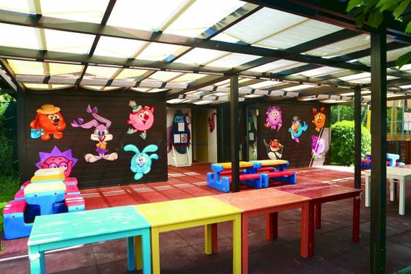 Spielbereich für Kinder unter einer Überdachung im Hotel Side Star Elegance mit bunten Tischen und Stühlen.