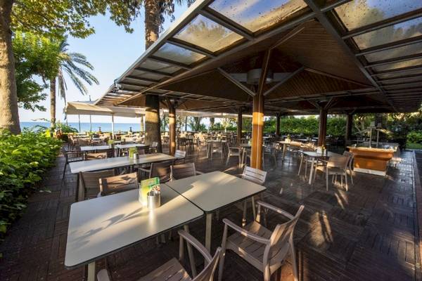 Terrasse des Side Star Elegance Hotels mit Tischen und Stühlen unter einem Dach.
