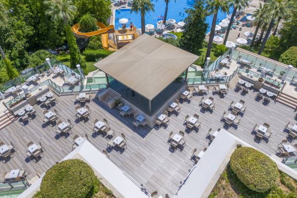 Luftaufnahme der Terrasse des Side Star Elegance Hotels mit Swimmingpool, Wasserrutsche und vielen Tischen.