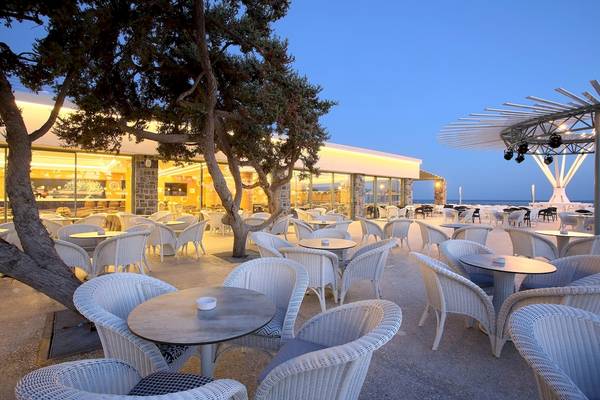 Außenbereich des Arina Beach Resorts bei Nacht mit vielen weißen Tischen und Stühlen.