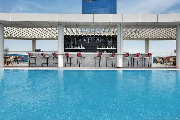 Poolbar des NH Collection Dubai The Palm Hotels mit roten Stühlen und schwarzem Tresen