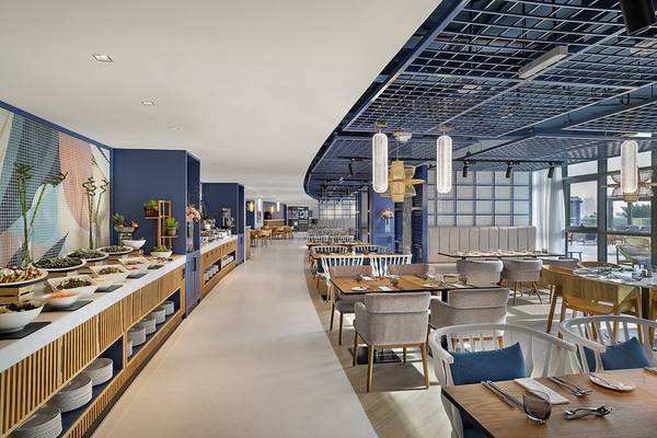Innenansicht des Restaurants im NH Collection Dubai The Palm Hotel mit geometrischen Wänden und moderner Einrichtung.