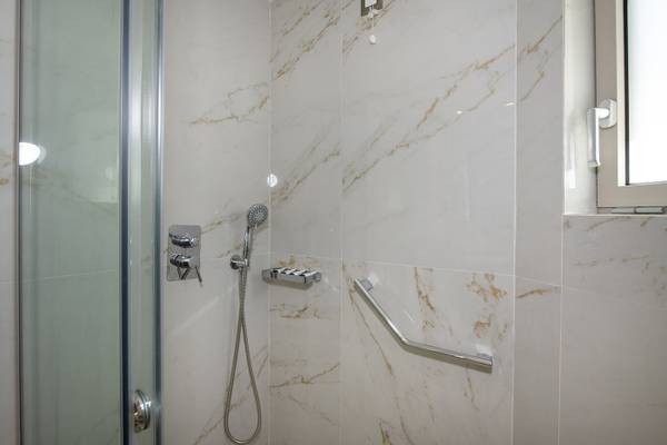 Eine Dusche mit marmorierten Wänden und Edelstahlgriffen im Vantari Luxury Beach Resort.