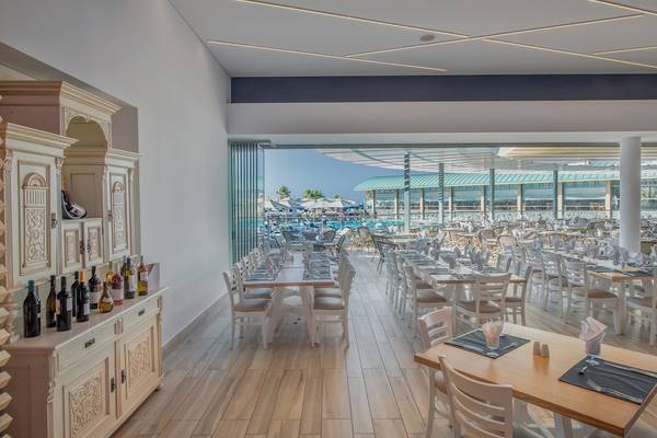 Innenansicht des Restaurants im Arina Beach Resort mit vielen gedeckten Tischen und einer Aussicht auf den Poolbereich.