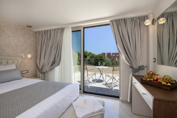 Innenansicht eines Schlafzimmers im Vantaris Luxury Beach Resort mit Balkon und Obstkorb.