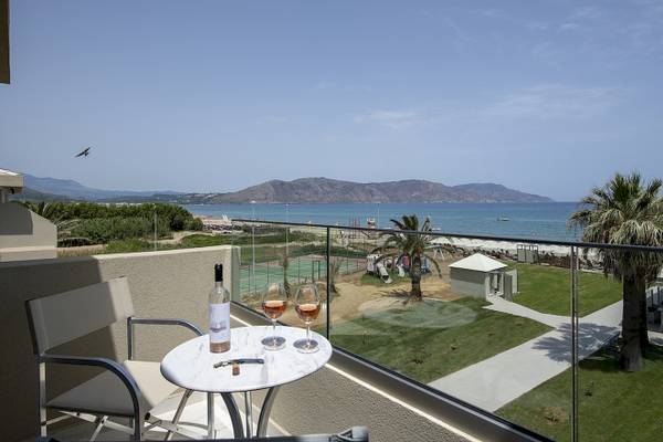 Terrasse mit Meerblick im Vantaris Luxury Beach Resort mit Tisch, Wein und Blick auf das Meer.
