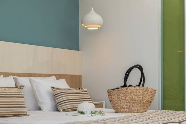 Arina Beach Resort Hotelzimmer mit Bett, Kissen, Hut und Korb auf dem Bett