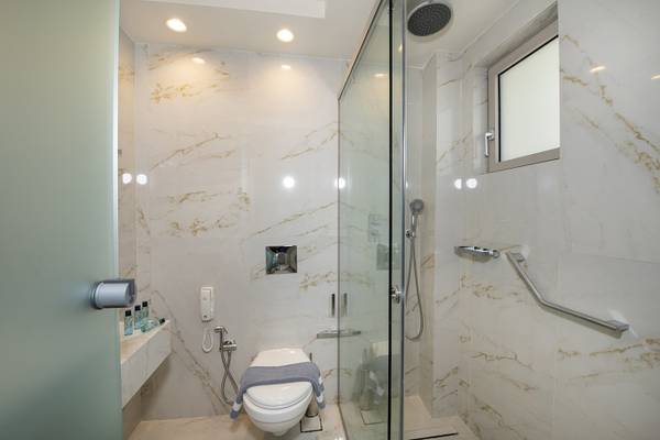 Badezimmer im Vantaris Luxury Beach Resort mit Marmorwänden, Duschkabine und Toilette.