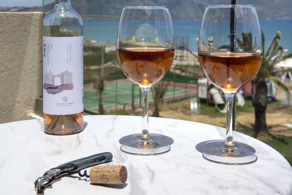 Eine Flasche Wein, zwei Gläser und ein Korkenzieher auf einem Tisch am Strand.