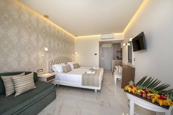 Hotelzimmer im Vantaris Luxury Beach Resort mit zwei Betten, Fernseher und Früchten.