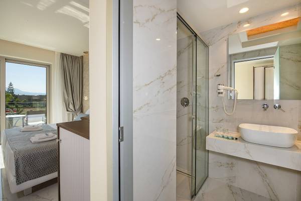 Suite Zimmer mit Dusche und Bett im Vantaris Luxury Beach Resort