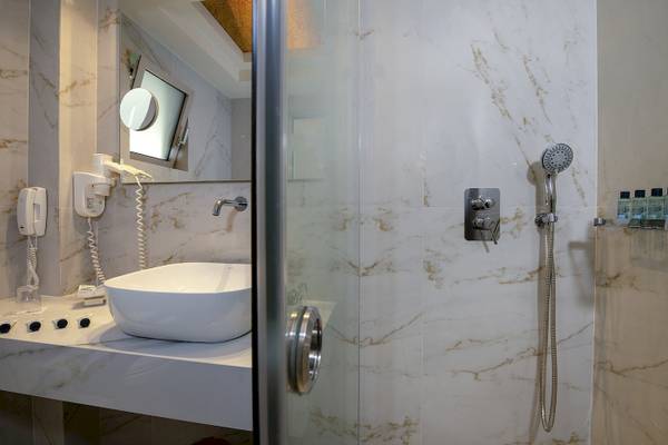 Badezimmer im Vantaris Luxury Beach Resort mit weißem Waschbecken und Marmorwänden.