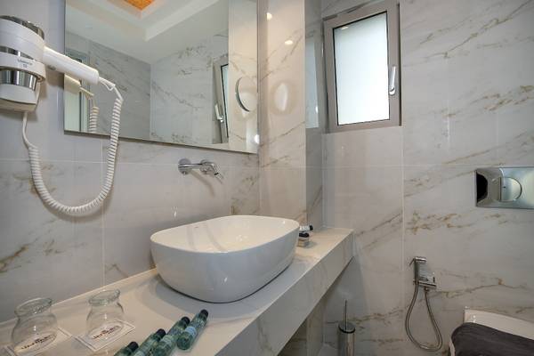Badezimmer im Vantaris Luxury Beach Resort mit weißer Marmorfliesen und einem Waschbecken.