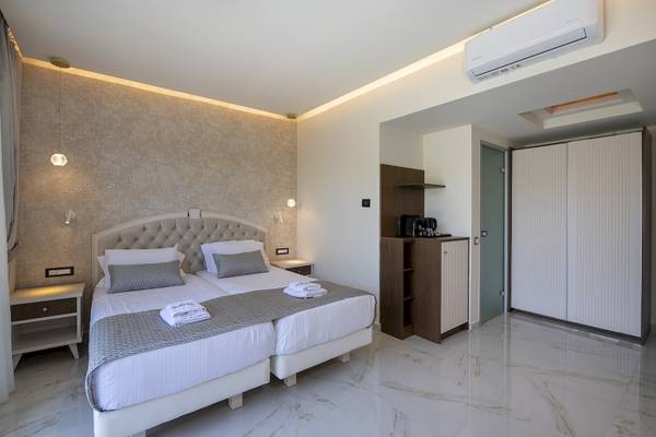 Doppelbett-Schlafzimmer im Vantaris Luxury Beach Resort mit weißen Möbeln und Marmorböden.