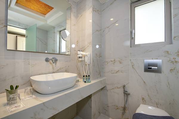Vantaris Luxury Beach Resort Badezimmer mit weißer Marmorwand, großer Spiegel und luxuriösem Waschbecken.