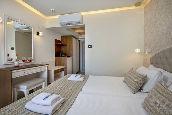 Doppelbettzimmer im Vantaris Luxury Beach Resort Hotel mit Klimaanlage, Spiegel und Weinflaschen.