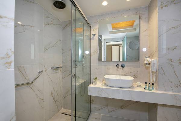 Badezimmer im Vantaris Luxury Beach Resort mit Marmorwänden und einer Dusche.