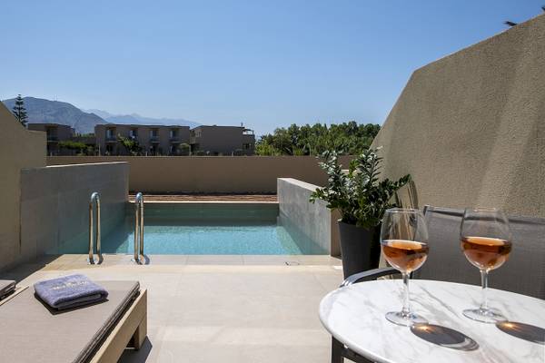 Vantaris Luxury Beach Resort Poolbereich mit Sonnenliegen und Weingläsern auf einem Marmortisch.