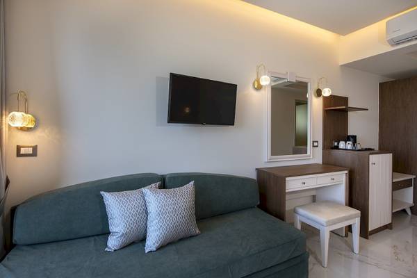 Zimmer im Vantaris Luxury Beach Resort mit Fernseher, Spiegel, Lampe und Schreibtisch