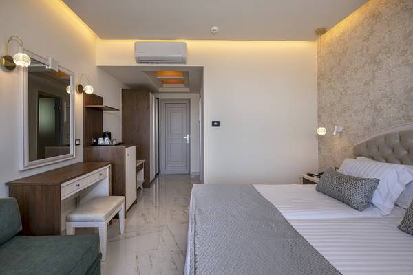 Hotelzimmer im Vantaris Luxury Beach Resort mit Doppelbett, Spiegel, Nachttisch und Klimaanlage.