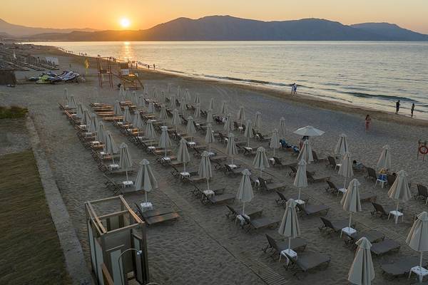Luftaufnahme des Vantaris Luxus Strandresorts bei Sonnenuntergang mit vielen Sonnenliegen und Schirmen am Strand.