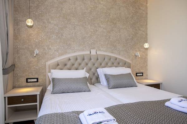 Doppelbettzimmer im Vantaris Luxury Beach Resort mit gemusterten Laken und Kissen.