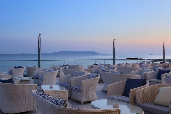 Terrasse des Arina Beach Resorts mit Blick auf den Ozean bei Sonnenuntergang.