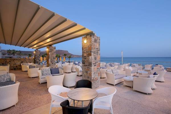 Außenterrasse des Arina Beach Resorts mit Blick auf das Meer und weißen Sesseln.