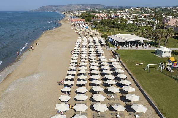 Luftaufnahme des Vantaris Luxury Beach Resorts mit vielen Sonnenschirmen und Gästen am Strand.