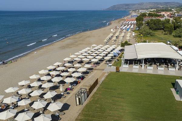 Luftaufnahme des Vantaris Luxury Beach Resorts mit vielen Sonnenschirmen am Strand und einer großen Terrasse.