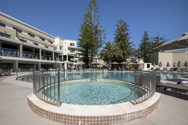 Außenbereich des Vantaris Luxury Beach Resort mit Pool, Sonnenliegen und Schirmen.
