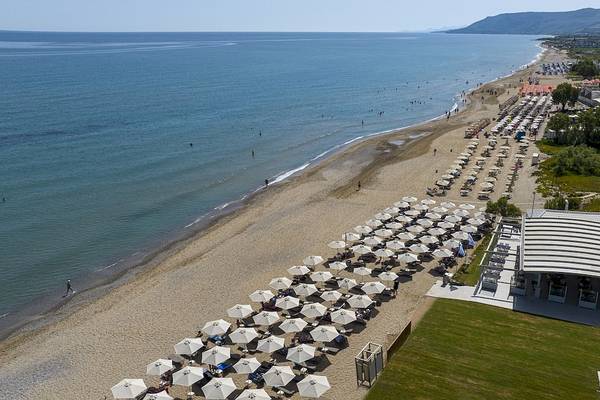 Luftaufnahme des Vantaris Luxury Beach Resorts mit Strand, Meer und vielen Sonnenschirmen.