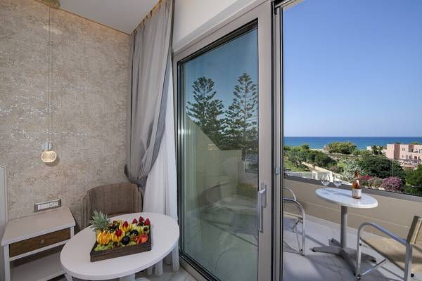 Balkon mit Meerblick im Vantaris Luxury Beach Resort mit Früchtetablett und Weinflasche.