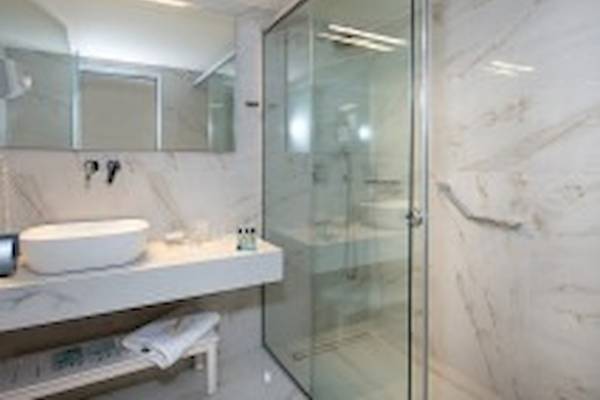 Badezimmer im Vantaris Luxury Beach Resort mit weißen Marmorwänden und einer Glasdusche.