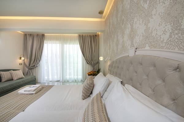 Hotelzimmer im Vantaris Luxury Beach Resort mit zwei Betten, Kissen und einem Sofa.