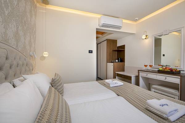 Schlafzimmer im Vantaris Luxury Beach Resort mit zwei Betten, weißen Kissen, und einer Kommode mit Früchten.