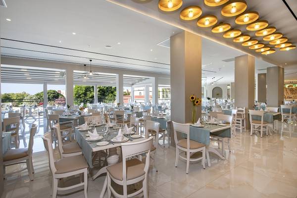 Innenansicht des Restaurants im Vantaris Luxury Beach Resort mit runden Deckenleuchten und gedeckten Tischen.