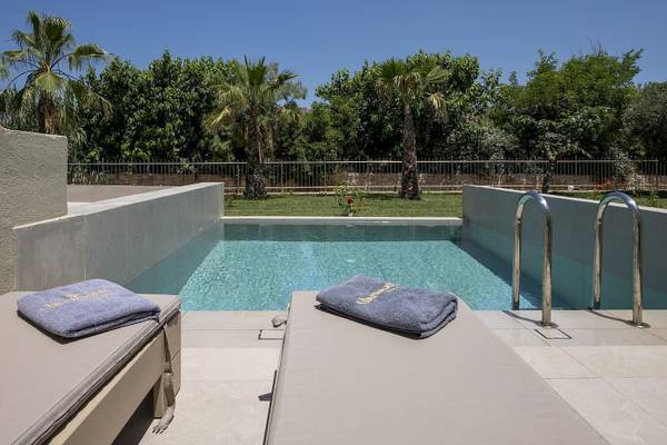 Loungebereich am Pool des Vantaris Luxury Beach Resorts mit zwei Liegen und Handtüchern.