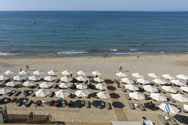 Luftaufnahme des Vantaris Luxury Beach Resort Strands mit vielen Sonnenschirmen und Liegen