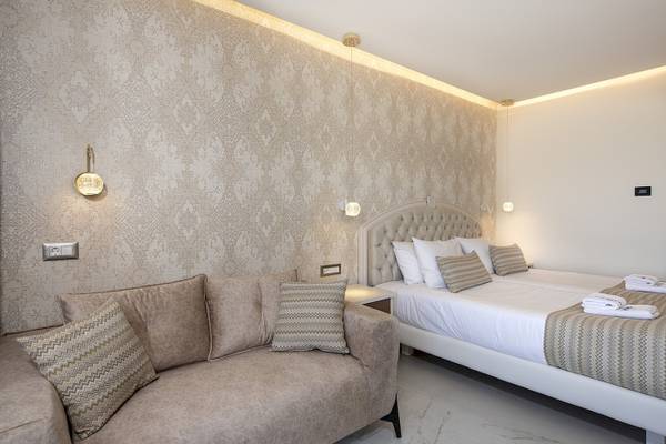 Schlafzimmer im Vantaris Luxury Beach Resort mit Doppelbett und Sofa.