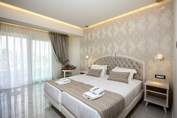 Schlafzimmer im Vantaris Luxury Beach Resort mit zwei Betten, weißen Vorhängen und Dekor.