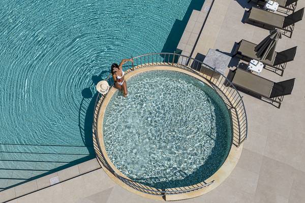 Luftaufnahme des Infinity-Pools im Vantaris Luxury Beach Resort mit einer Frau in der Mitte.