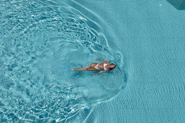 Luftaufnahme einer Frau, die im Schwimmbad des Vantari Luxury Beach Resorts schwimmt.