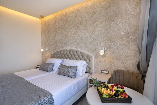 Hotelzimmer des Vantaris Luxury Beach Resort mit zwei Betten und einer Obstplatte auf dem Tisch.