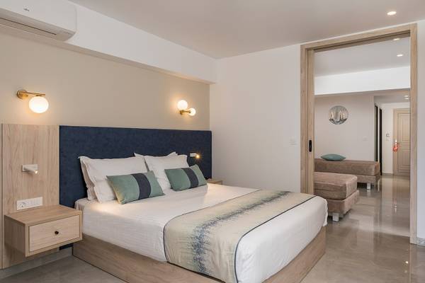 Innenansicht des Schlafzimmers im Vantaris Palace mit Bett, Nachttischen und offenem Badezimmer.