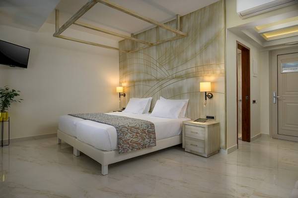 Elegantes Hotelzimmer mit weißem Bett, Tisch, Lampe und Fernseher.