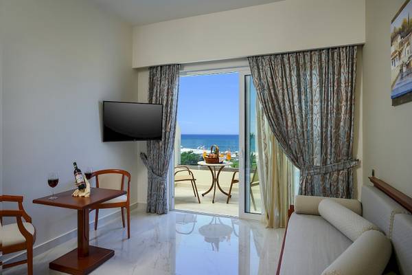 Suite mit Meerblick im Vantaris Palace mit einem Tisch, zwei Stühlen, einem Fernseher und einem Balkon.
